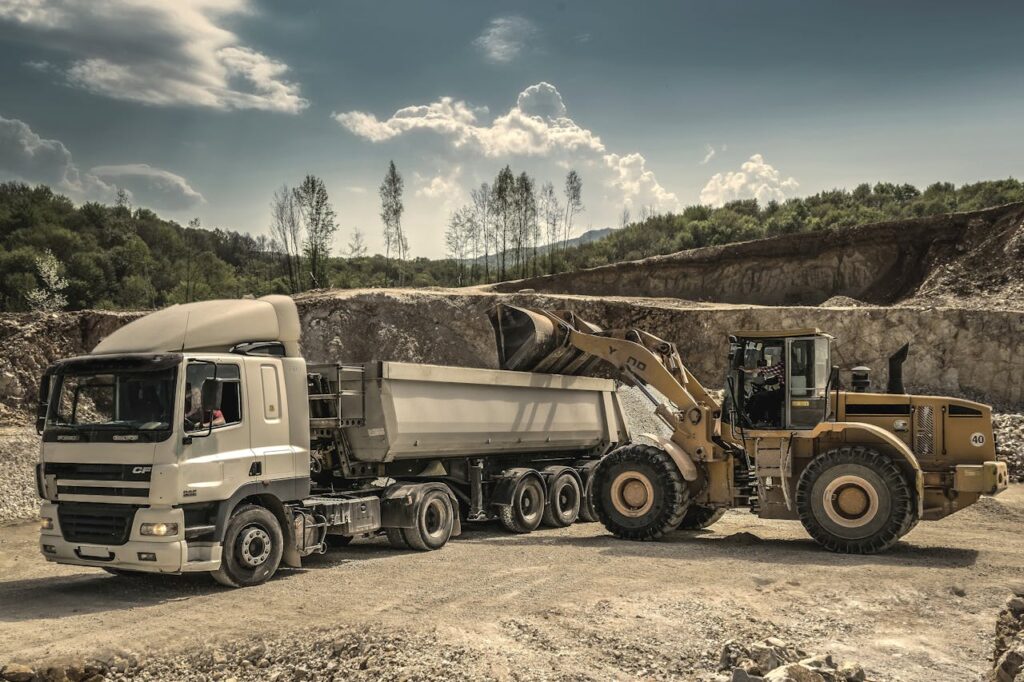 Front Load Loader Beside White Dump Truck